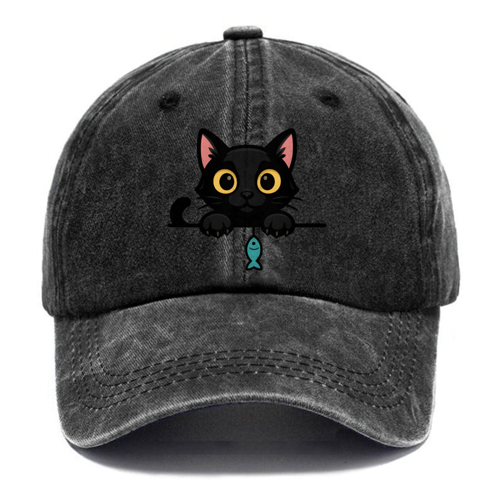 Midnight the black cat holding a tiny yarn ball between both paws while peeking Washed Cap