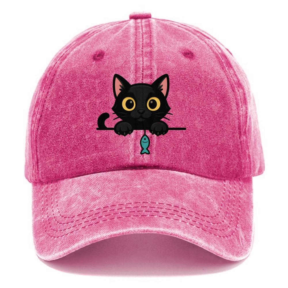 Midnight the black cat holding a tiny yarn ball between both paws while peeking Washed Cap