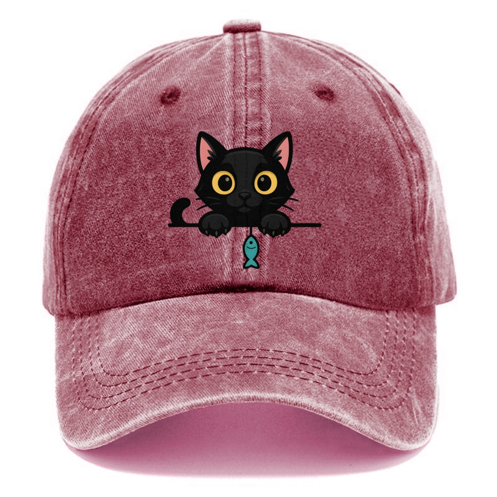 Midnight the black cat holding a tiny yarn ball between both paws while peeking Washed Cap
