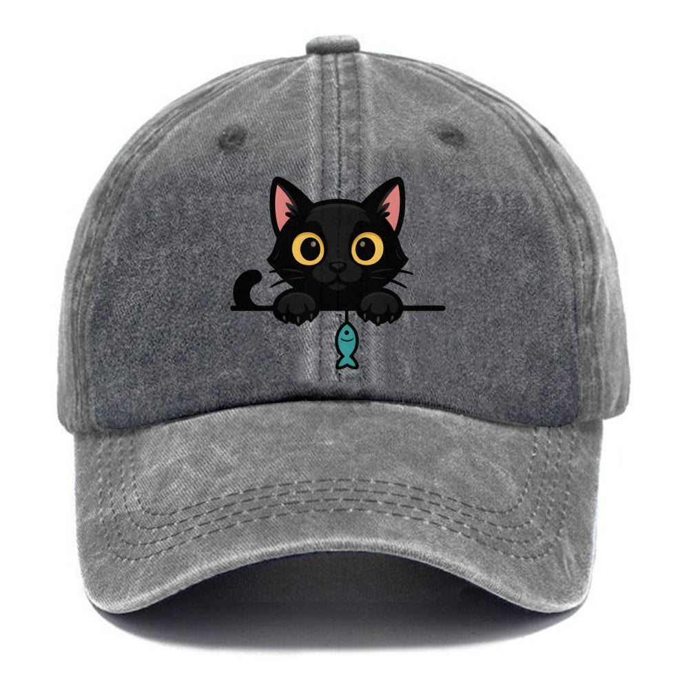 Midnight the black cat holding a tiny yarn ball between both paws while peeking Washed Cap