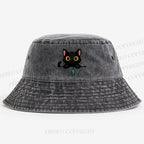 Midnight the black cat holding a tiny yarn ball between both paws while peeking Washed Bucket Hat
