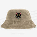 Midnight the black cat holding a tiny yarn ball between both paws while peeking Washed Bucket Hat