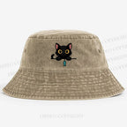 Midnight the black cat holding a tiny yarn ball between both paws while peeking Washed Bucket Hat