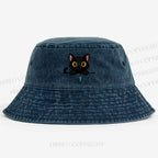 Midnight the black cat holding a tiny yarn ball between both paws while peeking Washed Bucket Hat