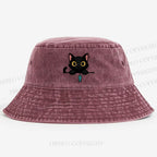 Midnight the black cat holding a tiny yarn ball between both paws while peeking Washed Bucket Hat